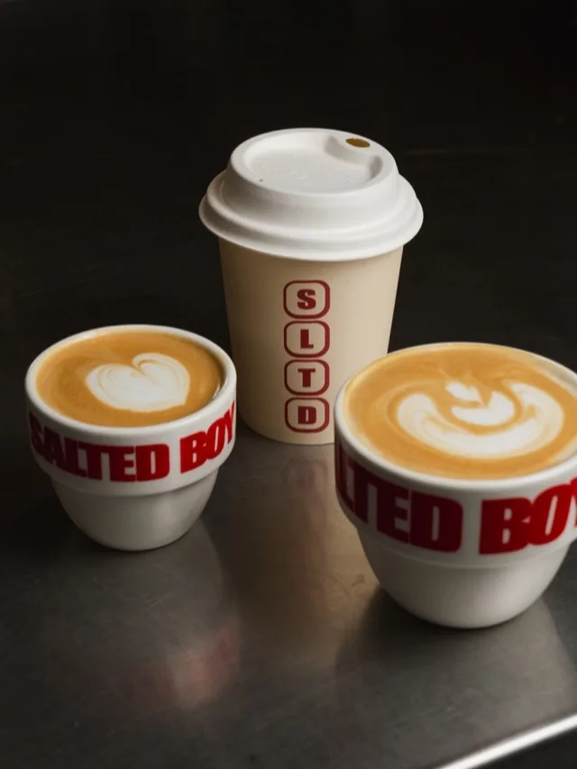 Deux cafés latte art en tasses Salted Boy et un gobelet SLTD.
